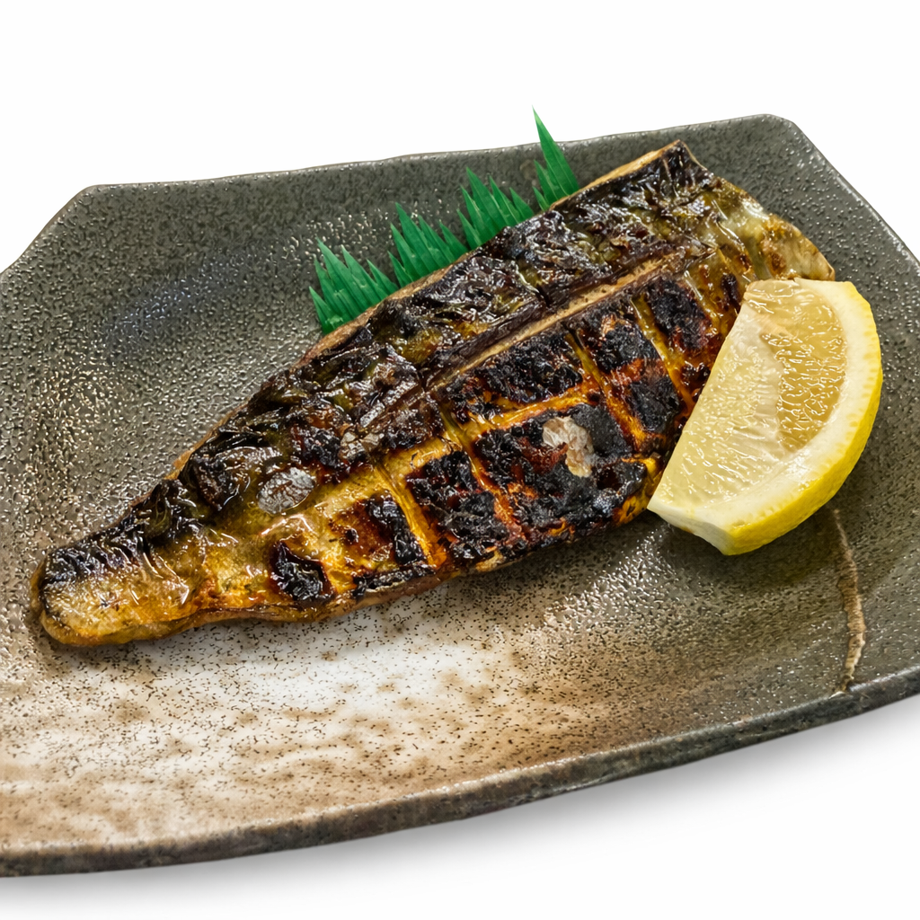Grilled fish fillet on a ceramic plate with a lemon wedge and green garnish.